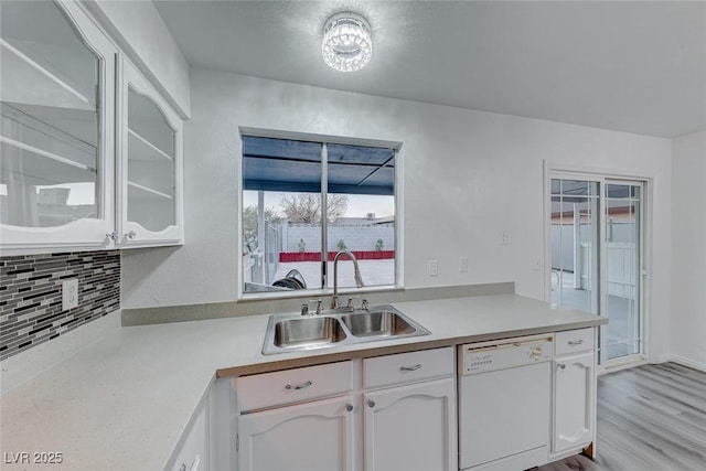 kitchen with white cabinetry, dishwasher, sink, backsplash, and light wood-type flooring