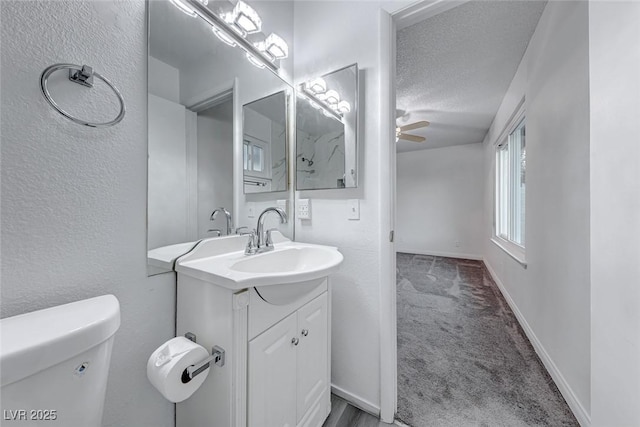 bathroom with ceiling fan, vanity, a textured ceiling, and toilet