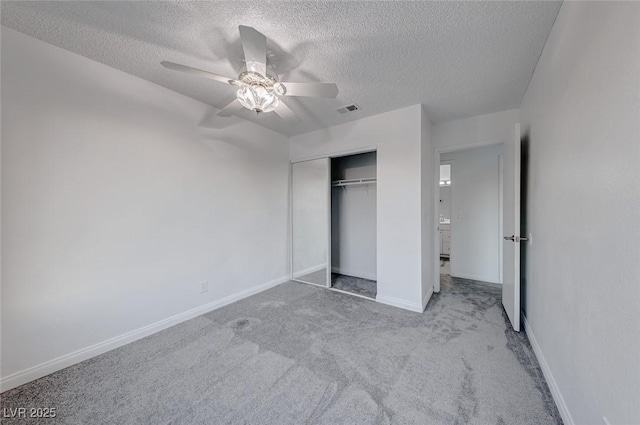 unfurnished bedroom featuring a textured ceiling, a closet, ceiling fan, and light colored carpet