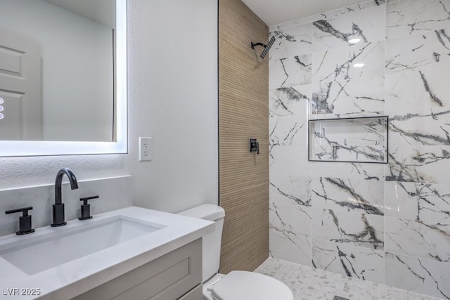 bathroom featuring tiled shower, vanity, and toilet