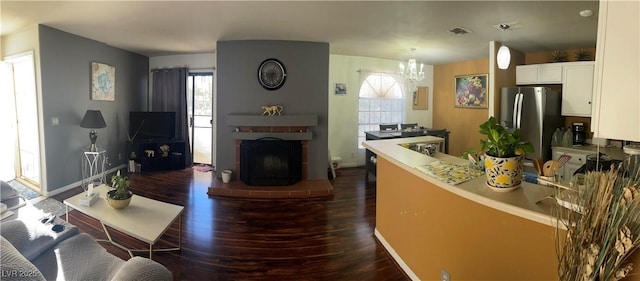 kitchen featuring pendant lighting, a fireplace, dark hardwood / wood-style flooring, white cabinetry, and stainless steel refrigerator