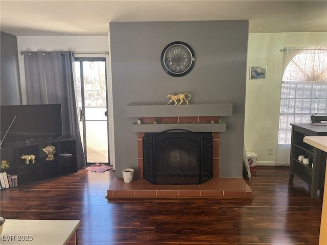 living room featuring a tile fireplace and dark wood-type flooring