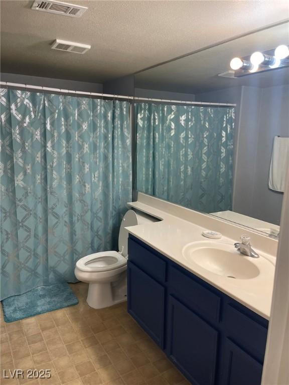 bathroom featuring vanity, a textured ceiling, and toilet