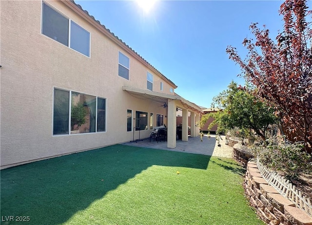 rear view of property featuring a lawn, ceiling fan, and a patio area