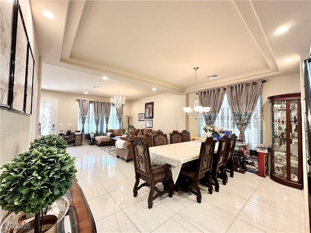 dining room with a raised ceiling, a wealth of natural light, and a chandelier