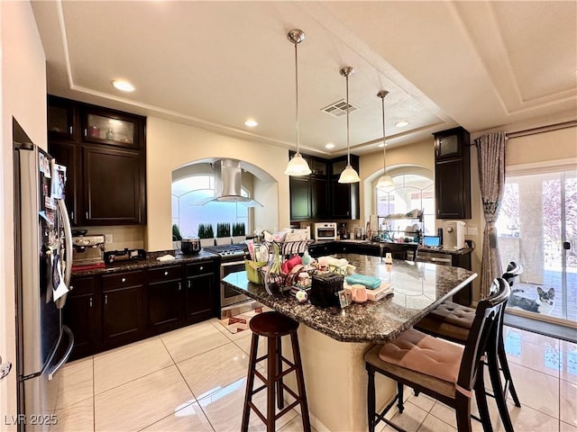 kitchen featuring a kitchen island, decorative light fixtures, a breakfast bar area, light tile patterned floors, and appliances with stainless steel finishes