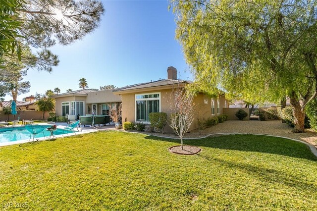 rear view of house with a fenced in pool and a lawn