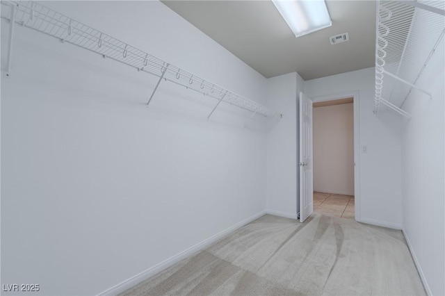 walk in closet with light carpet