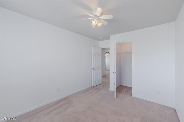 unfurnished bedroom with ceiling fan, light carpet, a closet, and a walk in closet