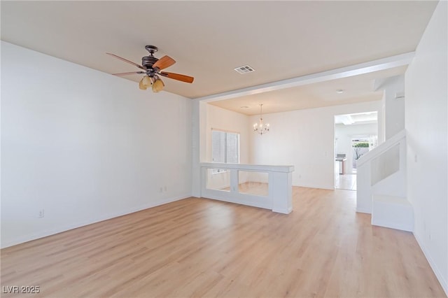 spare room featuring ceiling fan with notable chandelier and light hardwood / wood-style floors