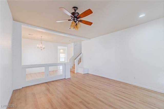 empty room with light wood-type flooring and ceiling fan with notable chandelier