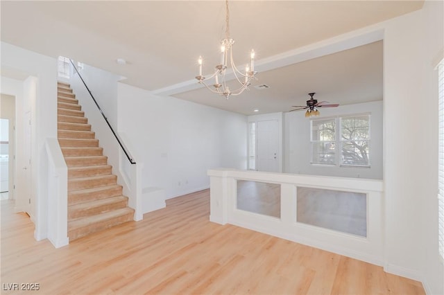 spare room featuring beamed ceiling, ceiling fan with notable chandelier, and hardwood / wood-style floors