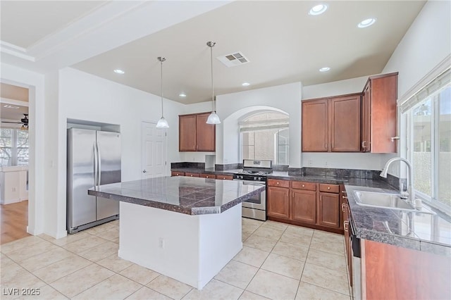 kitchen with ceiling fan, a center island, sink, light tile patterned flooring, and appliances with stainless steel finishes