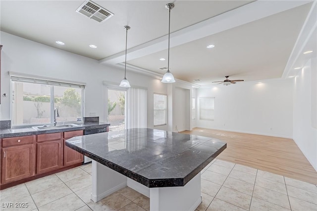 kitchen featuring light tile patterned flooring, ceiling fan, a kitchen island, and sink