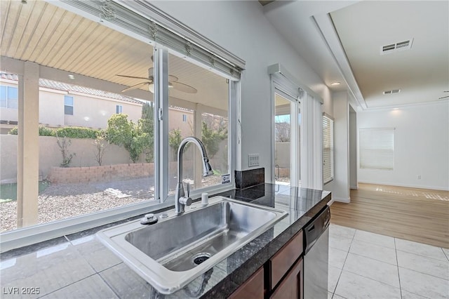 kitchen with sink, a wealth of natural light, stainless steel dishwasher, and light tile patterned flooring