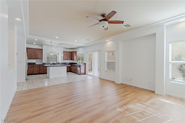 unfurnished living room featuring ceiling fan, a wealth of natural light, and light hardwood / wood-style flooring