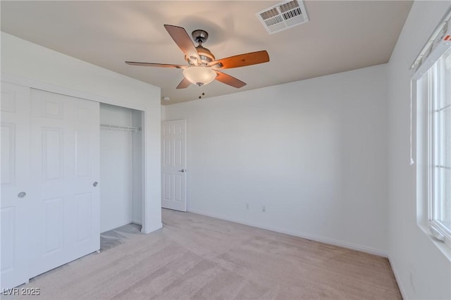 unfurnished bedroom featuring ceiling fan, a closet, and light colored carpet