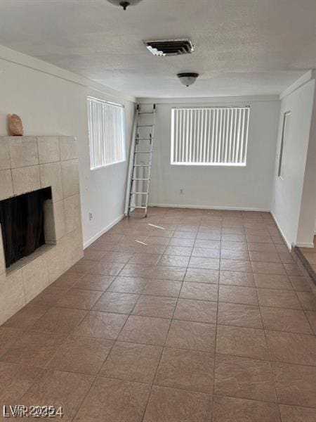 unfurnished living room with a tile fireplace, crown molding, and tile patterned flooring