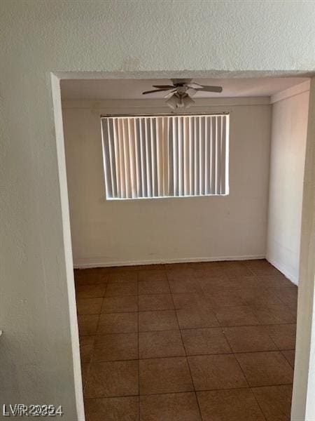 tiled empty room featuring ceiling fan