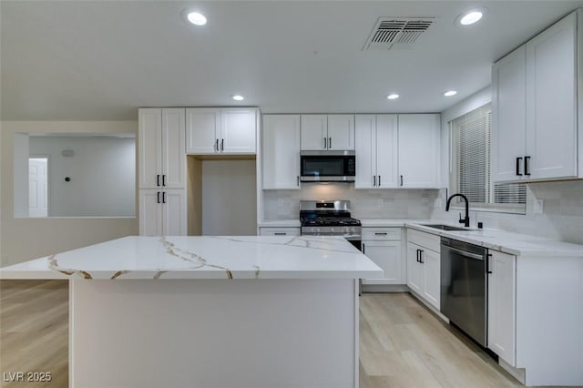 kitchen featuring appliances with stainless steel finishes, white cabinetry, and sink