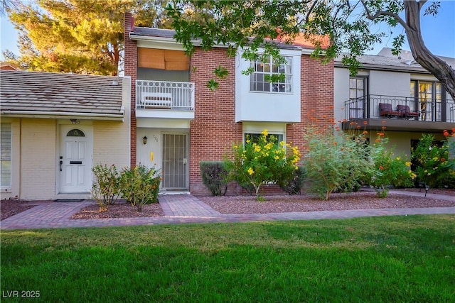 multi unit property with a balcony and a front lawn