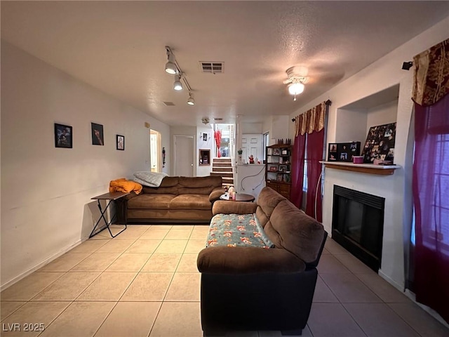 tiled living room featuring rail lighting and a textured ceiling