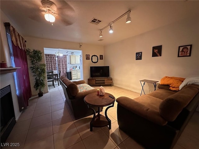 living room featuring ceiling fan with notable chandelier, rail lighting, and light tile patterned flooring