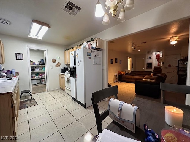 kitchen with a chandelier, white appliances, sink, and light tile patterned flooring