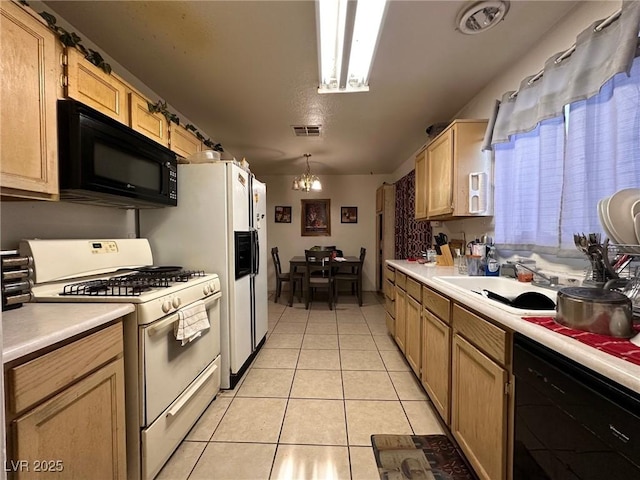 kitchen featuring sink, black appliances, light tile patterned floors, decorative light fixtures, and an inviting chandelier