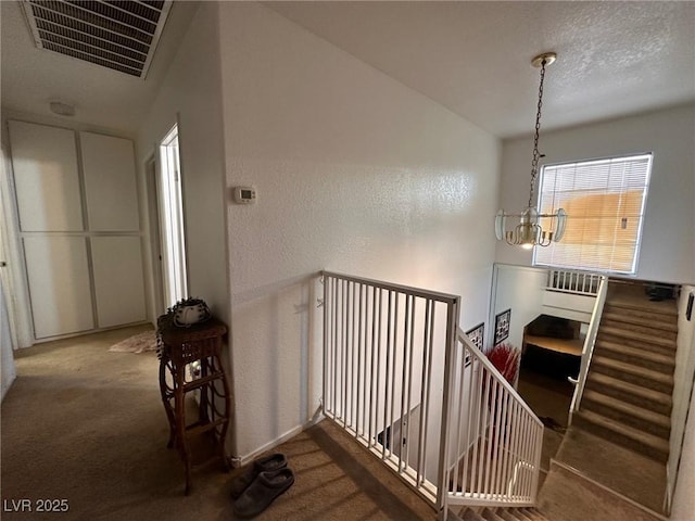 stairs featuring carpet and a notable chandelier