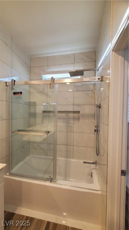 bathroom with hardwood / wood-style floors, vanity, and enclosed tub / shower combo