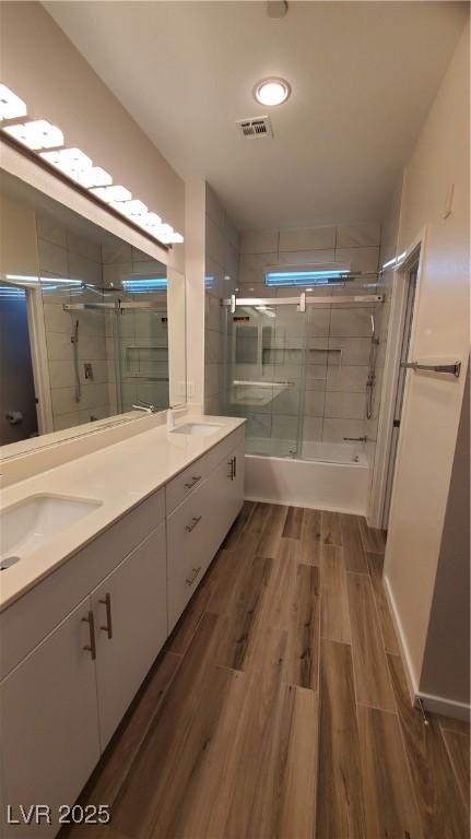 11251 Hidden Peak Ave Unit 212, Las Vegas, NV 89135 - full bathroom with double vanity, wood finish floors, visible vents, bath / shower combo with glass door, and a sink