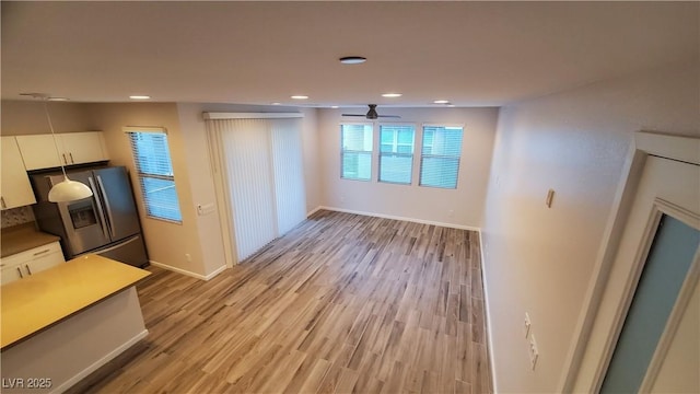 interior space featuring white cabinets, stainless steel fridge with ice dispenser, light hardwood / wood-style floors, and ceiling fan