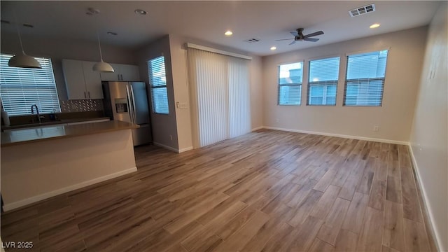 kitchen with ceiling fan, tasteful backsplash, stainless steel fridge with ice dispenser, pendant lighting, and light hardwood / wood-style floors