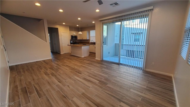 unfurnished living room featuring ceiling fan, sink, and wood-type flooring