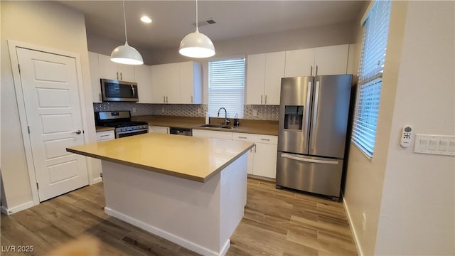 kitchen featuring white cabinets, sink, a center island, and appliances with stainless steel finishes