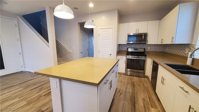 kitchen with sink, a center island, pendant lighting, white cabinets, and appliances with stainless steel finishes