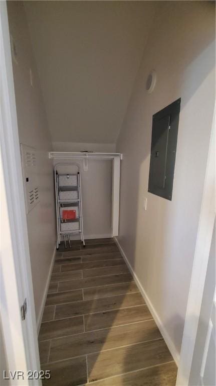 staircase with electric panel, wood-type flooring, and vaulted ceiling