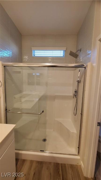 bathroom with wood-type flooring, vanity, and a shower with door