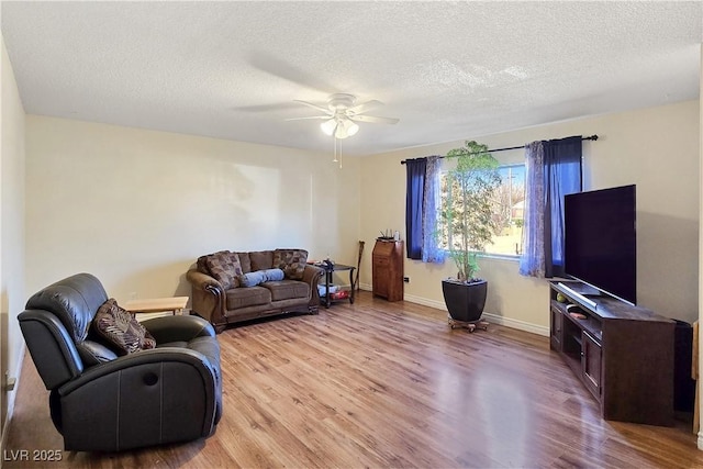 living room featuring ceiling fan, light hardwood / wood-style flooring, and a textured ceiling