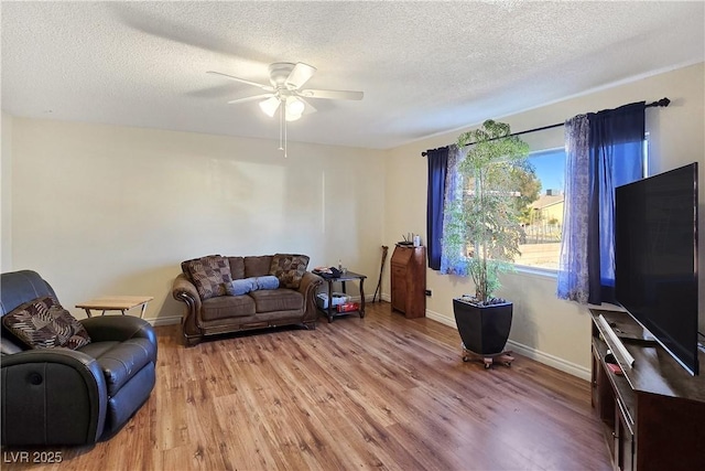 living room with ceiling fan, light hardwood / wood-style flooring, and a textured ceiling