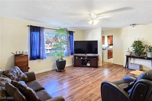 living room with ceiling fan, light hardwood / wood-style floors, and a textured ceiling