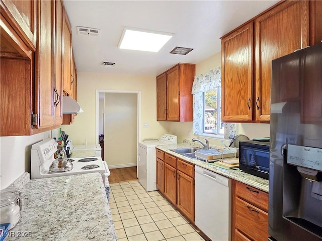 kitchen featuring light stone counters, white appliances, sink, and washing machine and clothes dryer