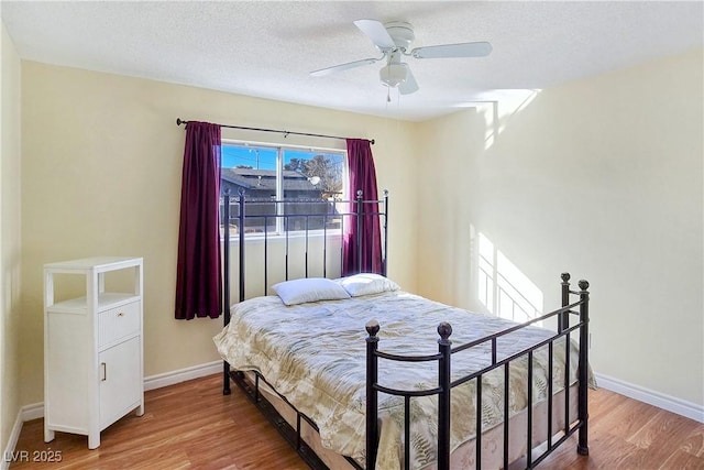 bedroom with hardwood / wood-style floors, a textured ceiling, and ceiling fan