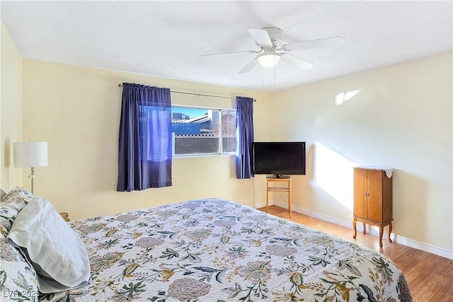 bedroom with multiple windows, ceiling fan, a textured ceiling, and hardwood / wood-style flooring