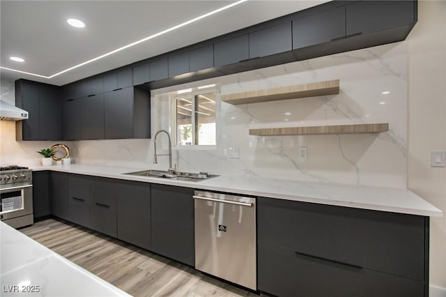 kitchen with light stone countertops, sink, tasteful backsplash, light hardwood / wood-style flooring, and appliances with stainless steel finishes