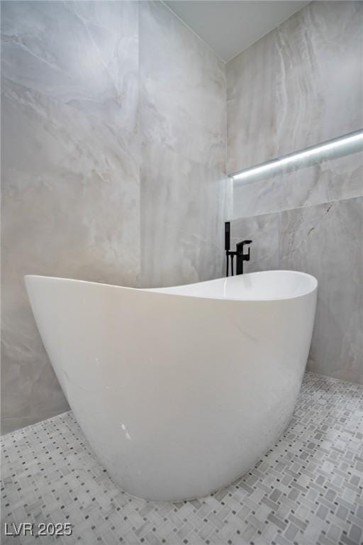 bathroom featuring tile patterned flooring, a bath, and tile walls