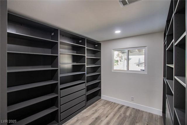 walk in closet with light hardwood / wood-style floors