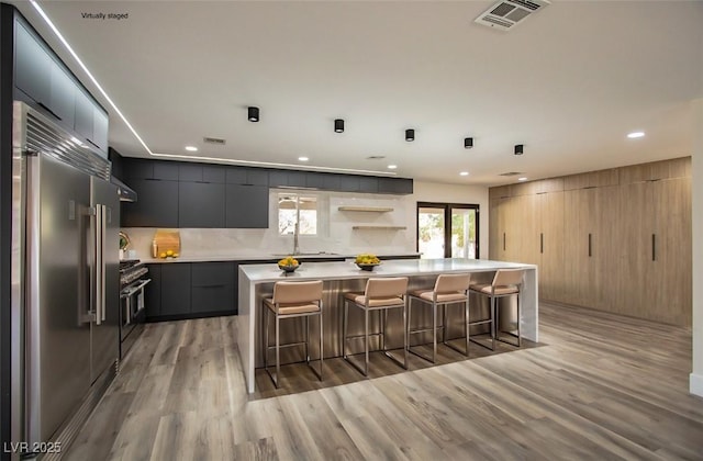 kitchen featuring a breakfast bar, a kitchen island, stainless steel appliances, and light hardwood / wood-style flooring