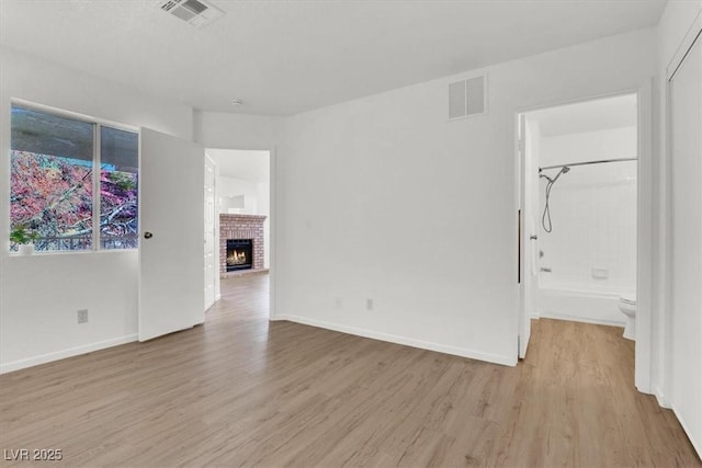 empty room featuring light hardwood / wood-style floors and a brick fireplace